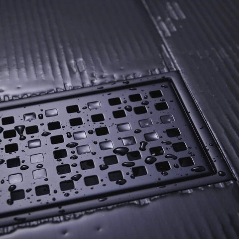 Close-up of Linear Shower Floor Drain With Removable Cover Grid Grate 12 Inch Long Rectangle Stainless Steel Matte Black Finish For Modern Bathrooms Premium 304 Stainless Steel Construction Scratch Resistant Corrosion Resistant Built Tough with water droplets