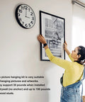 Woman hanging artwork with Heavy Duty Picture Hangers And Double Headed Wall Hooks With Bulletproof Grip Rating Up To 30 Lbs For Drywall Or Wood Studs Zero Hassle Setup Hang Gallery Walls Without Sweat Includes 30 Pack.