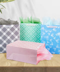 Party Ready 12 Pack Gift Bags Assorted Sizes with Tissue Paper Bulk Set displayed on a table with four colorful bags.