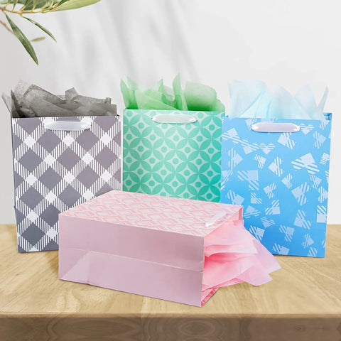 Party Ready 12 Pack Gift Bags Assorted Sizes with Tissue Paper Bulk Set displayed on a table with four colorful bags.