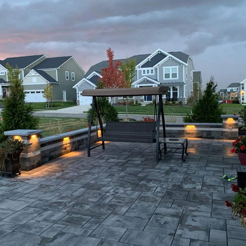 3-Way Dimmable LED Hardscape Lights Pack Of 4 illuminating a modern backyard patio at dusk with warm white light.