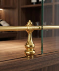 All Metal Railing Shelf Brackets Kit With Zinc Alloy Connectors And Golden Finish Bar Cart Rail Ends Decorative Cabinet Gallery Protects Glass Edges Pro Grade Build And Easy Indoor Installation For Glass Display, featuring close-up on golden bracket between glass and wood surface.