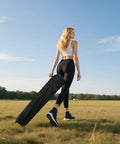 Person walking on grass, carrying black roller bag, representing 10x10 Pop Up Canopy Tent With One Button Push Setup Heavy Duty Outdoor Shelter