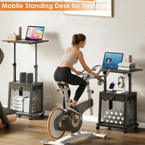 Height Adjustable Standing Desk On Wheels With Drawer And Storage beside exercise bike, showing laptop and storage