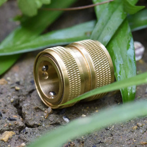 Side view of a Brass 4-Piece Quick Connect Garden Hose Fitting, heavy-duty adapter with grippy handle, on ground amid grass.