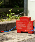 Heat Trip Automatic Fire Suppressor For Truck Engine Compartment Featuring Slick Snap On Install and Heavy Duty 360 Degree Coverage, red unit on ground.