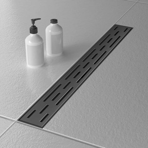 Black Linear Shower Drain 24 Inch Rectangular Floor Drain With Brick Pattern Cover For Modern Bathrooms Dope Stainless Steel Channel Drain 2 Inch Outlet Easy Maintenance next to two white bottles