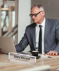 Man working at desk with 4 Pack Clear Acrylic Desk Name Plates Set With Double Sided Design, Personalized Office Name Tag Blocks visible.