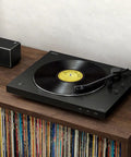 Sony PS-LX310BT Belt Drive Turntable Fully Automatic Wireless Vinyl Record Player on a wooden shelf with records nearby.