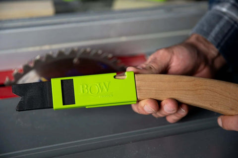 Green BOW PushPRO PP1 EVA-tipped push block held beside a table saw, side view, gripping a wooden board.