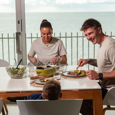 Family enjoying a meal with salad and steak, showcasing the Game Changing Glass Olive Oil Sprayer For Cooking, 16 Oz.