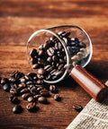 Single Spout Espresso Shot Glass With Wood Handle filled with coffee beans on a wooden table, showcasing borosilicate glass detail.