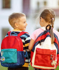 Two children with colorful backpacks featuring button badges from Epic 100 Pack Button Maker Kit For DIY Badges 2.25 Inch Metal Shells.