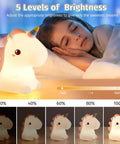 Child sleeping next to illuminated Unicorn Night Light For Kids With Sound Machine, 16 Color Silicone Baby Night Lamp USB Rechargeable
