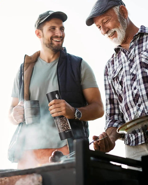 Two men using Upgraded Electric Salt And Pepper Grinder Set With Dual Charging Base at a barbecue.