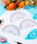 Bulk 100 Pack Clear Plastic Protractors 4 Inch Transparent Geometry Measuring Tools on paper with colored pencils.