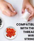 Hands threading spool with thin wire beside black and orange beads, showcasing compatibility of 40 Pack 12mm White Skull Beads For Jewelry Making.