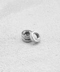 Two metal lock rings from Presta Valve Core Lock Ring Nuts Set 10 Pack Durable Metal Lock Rings For Presta Valves And Bicycle Inner Tubes Rust Resistant 5mm Inner Diameter 10mm Outer Fits Air Pumps And Compressors on textured surface