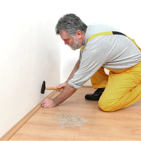 Man installing baseboard with double headed skirting nails with six sleeve tools for invisible seamless baseboard installation and trim.