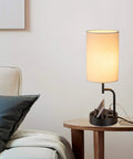 Cream bedside table lamp with three USB ports and AC outlet, phone stands, in modern living room, charging hub visible.