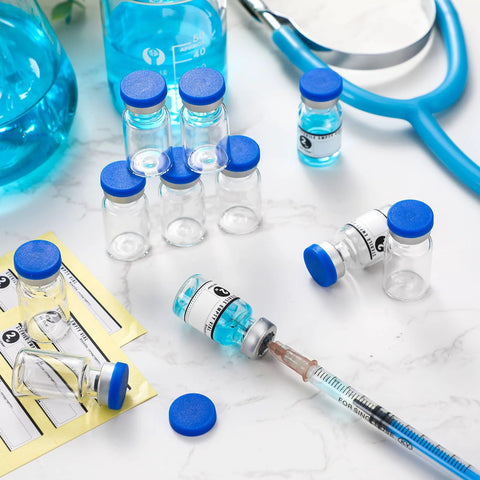 Front view of several 2ml glass vials with blue caps and labels beside a syringe on a lab counter.