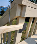 Side view of heavy-duty door barricade bracket installed, holding a 2x4 board for home security on outdoor wooden stairs.