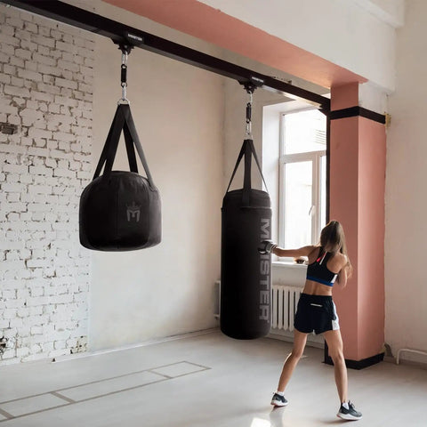 Rolling Beam Mount With Brakes For Heavy Bags Black 7.5 To 9.25 Inches in use, supporting boxing bags in a small gym setting.