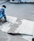 Worker applying Waterproof Underlayment For Concrete Slabs And Garage Deck Base 55ft High Density Polyethylene Membrane on surface.