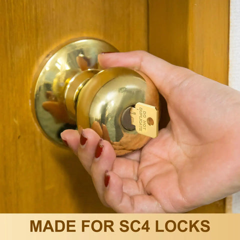 Person holding a door knob with a "Do Not Duplicate" gold key inserted. Bulk 50 Pcs Do Not Duplicate Metal Key Blanks For House Door Locks Gold SC4 Replacement Keys.