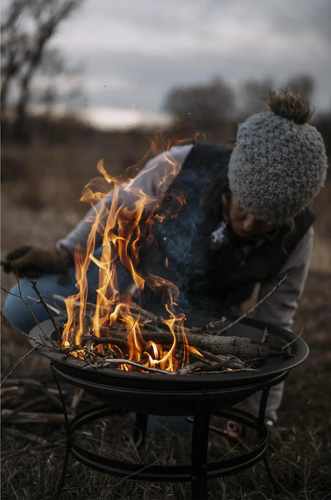 Person enjoying a campfire with a 22 Inch Outdoor Wood Burning Fire Pit With Mesh Lid And Fire Picker Durable Alloy Steel Pit.