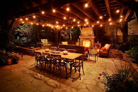 Outdoor patio scene with 25 Foot G40 Globe String Lights With 25 LED Bulbs For Indoor And Outdoor Use End To End Connectable UL Listed Candelabra E12 Sockets 12 Inch Bulb Spacing Warm White Glow For Home Decor And Commercial Events hanging above a dining table.