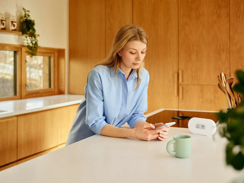 Battery Powered Indoor Air Quality Monitor With Wi Fi Connectivity For Radon PM2 5 CO2 VOC Humidity Temperature And Air Pressure Real Time Readouts displayed on kitchen counter