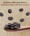 Realistic coffee bean pieces on a wooden spoon over a leaf background, highlighting full-bodied shape and clear textures.