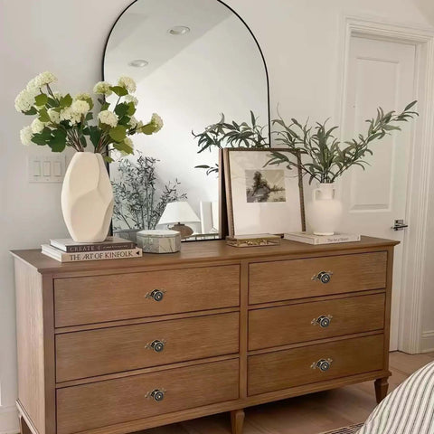 Wooden dresser with vintage mushroom round pulls, featuring Antique Brass Cabinet Knob Set With Backplates, decorated with books and vases.