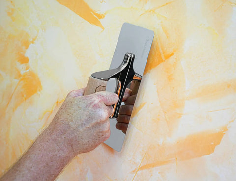 Hand using Venetian Plaster Trowel 240mm by 90mm with mirror polished 420 stainless steel blade on orange wall