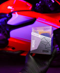 GYEON MOHS ceramic coating kit box held by gloved hand against a red motorcycle backdrop.