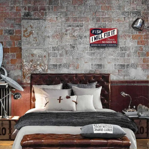 Vintage Metal Man Cave Sign For Men If I Say I Will Fix It There Is No Need To Remind Me Every 6 Months Funny Garage Wall Decor For Workshop Basement And Home Bar 12 X 8 Inches displayed on a brick wall above a bed in a bedroom setting.