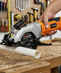 Extbtfor power circular saw with laser guide, orange body, cutting PVC pipe on a wood workbench.