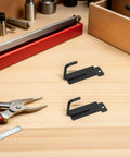 Heavy Duty Black Iron Candy Display Hooks, 15 Pack For Slat Wall Panels on a workbench with tools for easy install.
