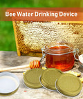 Eight Pack Mason Jar Bee Feeder Lids With Perforated Metal Entrance, gold finish, next to honeycomb and jar of syrup on table.