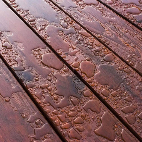 Heavy Duty Liquid Waterproofing Membrane Multi Surface Crack And Leak Repair Coating Interior Exterior Water Based Moisture Blocker Heavy Duty Sealant Easy Brush Application 5 Gallon Sandy Beige on wood surface with water droplets.