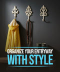 Distressed White Cast Iron Wall Hooks Set Of Three with a yellow coat and leashes hanging on a dark wall.