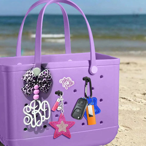 Purple beach tote with key holder insert charm carabiner for Bogg Bag, accessories visible on sandy beach with ocean backdrop.