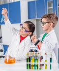 Two children in lab coats performing experiments in a science lab, wearing eyeglasses with side shields.