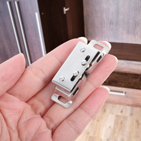 Close-up of Stainless Steel Ball Door Catch Latch Silver Finish Pack Of Ten Pairs with hand holding it near a cabinet door.