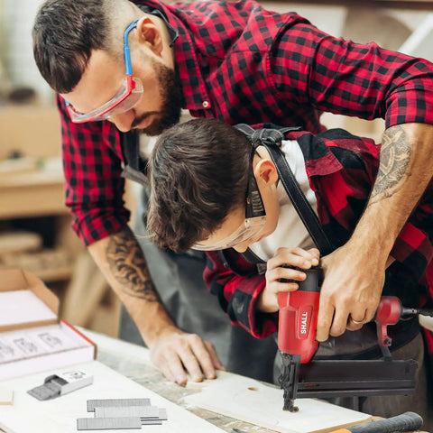 Man and child using pneumatic nailer with Pro Grade 18 Gauge Brad Nails Assortment 4000 Count Galvanized Nails
