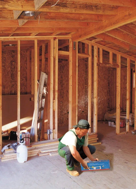 Worker holding a Pack of 4 Saf-T-Braces for Ceiling Fans with 3 Teeth Twist and Lock Silver Finish in unfinished room.