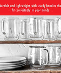Four Piece Double Wall Insulated Glass Coffee Mug Set Keeps Hot Brews Steaming And Icy Drinks Frosty With Zero Sweat Marks Premium Borosilicate Glass Is Dishwasher Safe For Your Daily Grind Routine on a shelf with white plates.