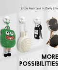 Wall hooks holding a green plush toy, a brush, a key fob, and sunglasses in a row
