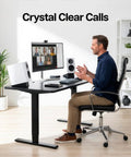 Man using desk setup with white speakers, highlighting Two Pack Desk Speaker Stands With 15 Degree Tilt For Bookshelf And Desktop Speakers 5 X 8 Inch Anti Vibration Risers For That Clean Loud Sound, Universal Fit, Studio Grade Audio Elevation, Black.